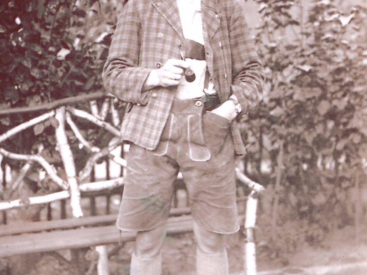 Herr in Jackett und Lederhose raucht Pfeife