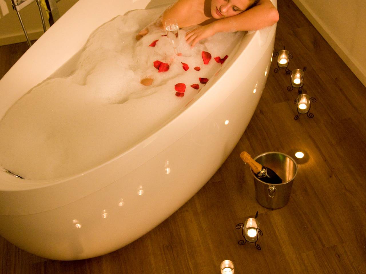 Frau in Whirlwanne mit Kerzen und Sekt