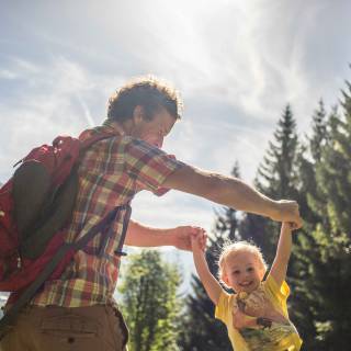 Vater spielt mit Kind im Hintergrund Wald & Berge